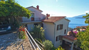 A coastal house with a stone pathway, a balcony, and a view of the sea. - Apartments Marisa 981 (Labin)