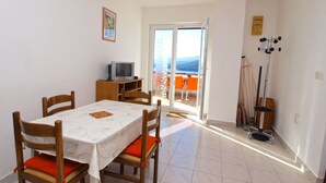A dining area with a table, chairs, and a television on a stand. - Apartments Marisa 981 (Labin)