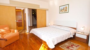 A bedroom with a bed, a chair, a nightstand, a lamp, and a painting on the wall. - Apartments Marisa 981 (Labin)
