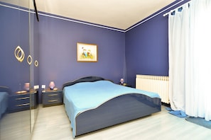 A bedroom with a bed, nightstands, a lamp, a painting, and a window with curtains. - Apartments Mila 1039 (Medulin)