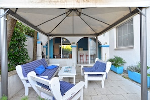 An outdoor patio with white furniture, including two sofas and a table, under a large umbrella. - Apartments Mila 1039 (Medulin)