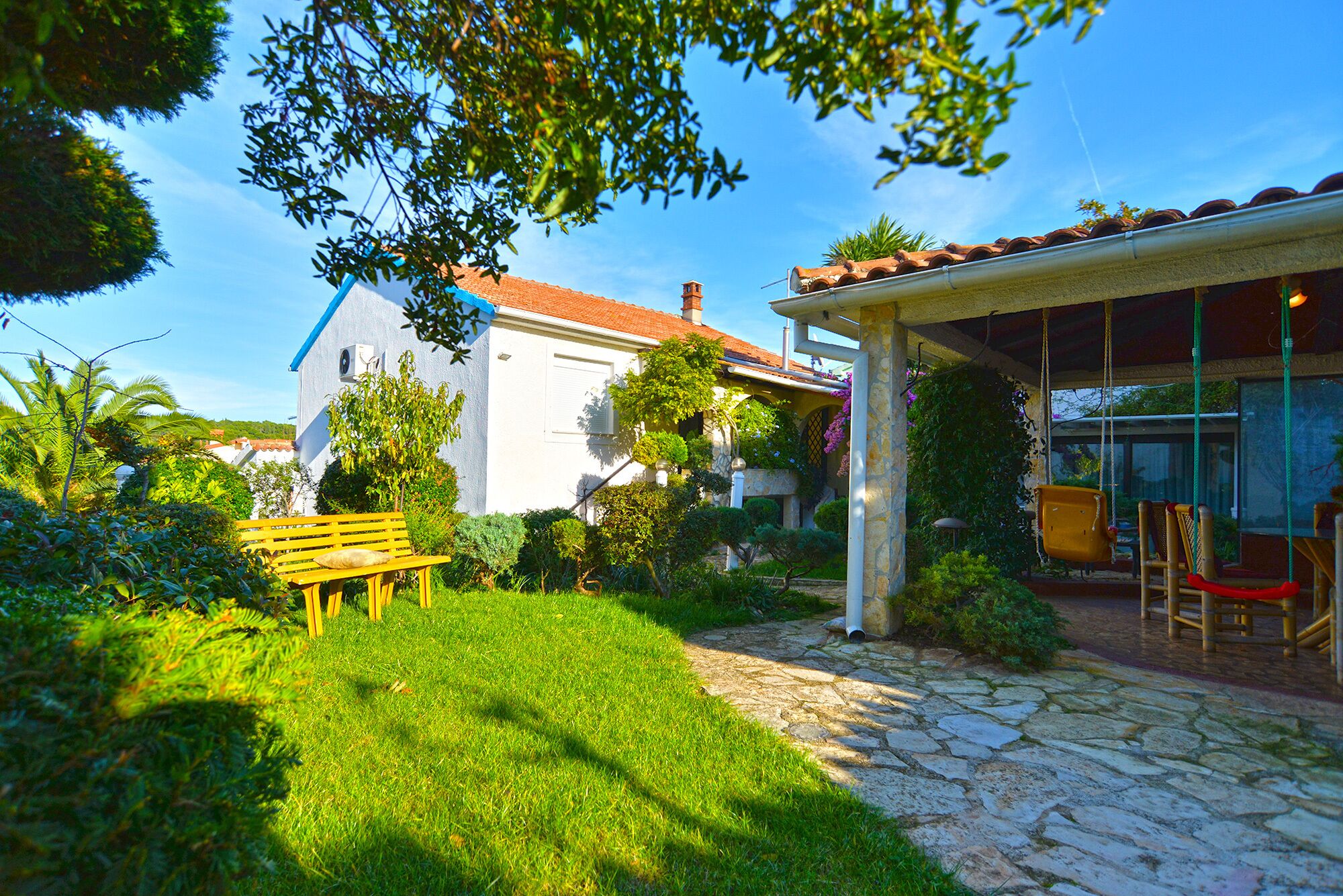 A house with a stone pathway leading to a covered patio area with outdoor furniture.