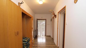 A hallway with patterned flooring, wooden cabinets, and a door with a striped curtain. - Rooms Milan 1370 (Rovinj)