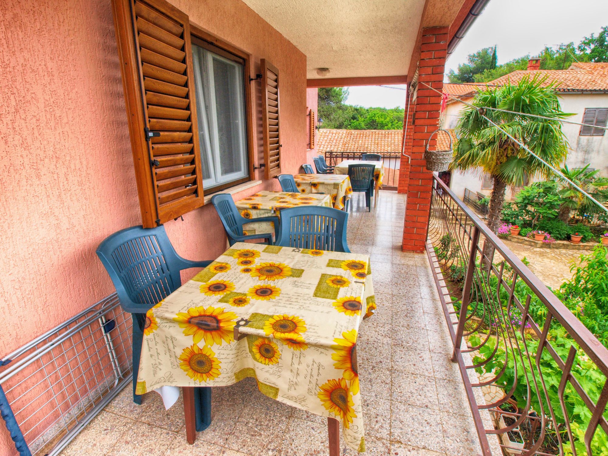 A balcony with tables and chairs, covered with sunflower-patterned tablecloths.