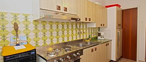 A compact kitchen with a gas stove, oven, and a refrigerator.