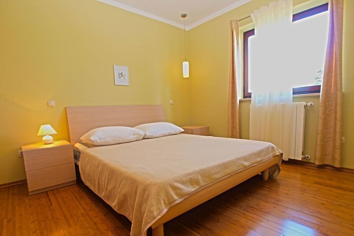 A neatly made bed with a wooden headboard, a bedside lamp, and a small bedside table.