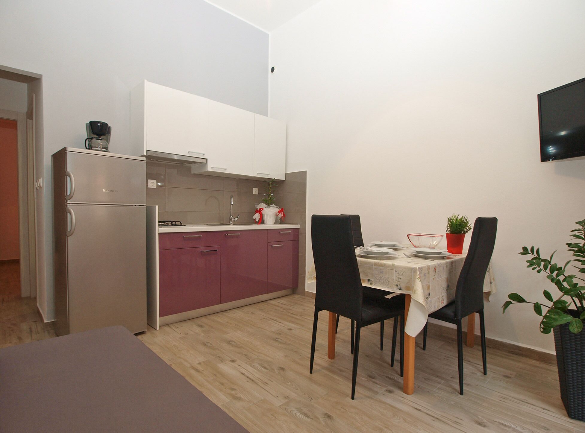 Une cuisine compacte équipée d’un réfrigérateur, d’un évier et d’un coin repas avec des chaises et une table.