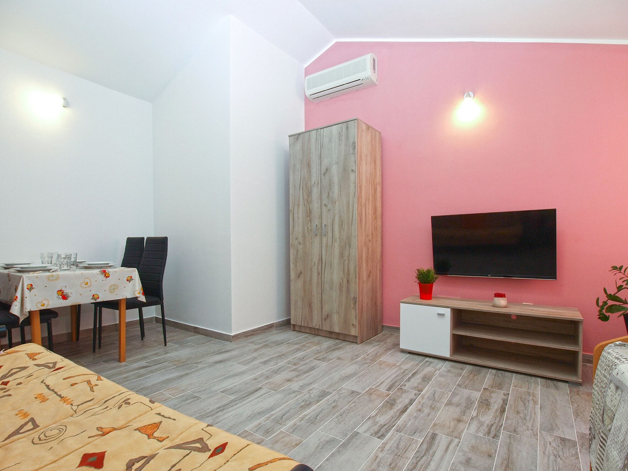 A room with a bed, a dining table with chairs, a TV, and a wardrobe.