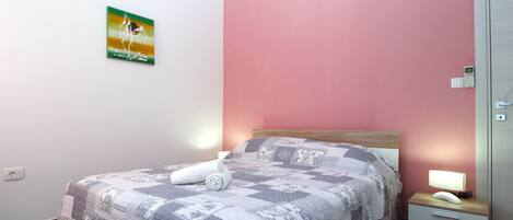 Un dormitorio con cama, mesita de noche, luz de pared e interruptor.