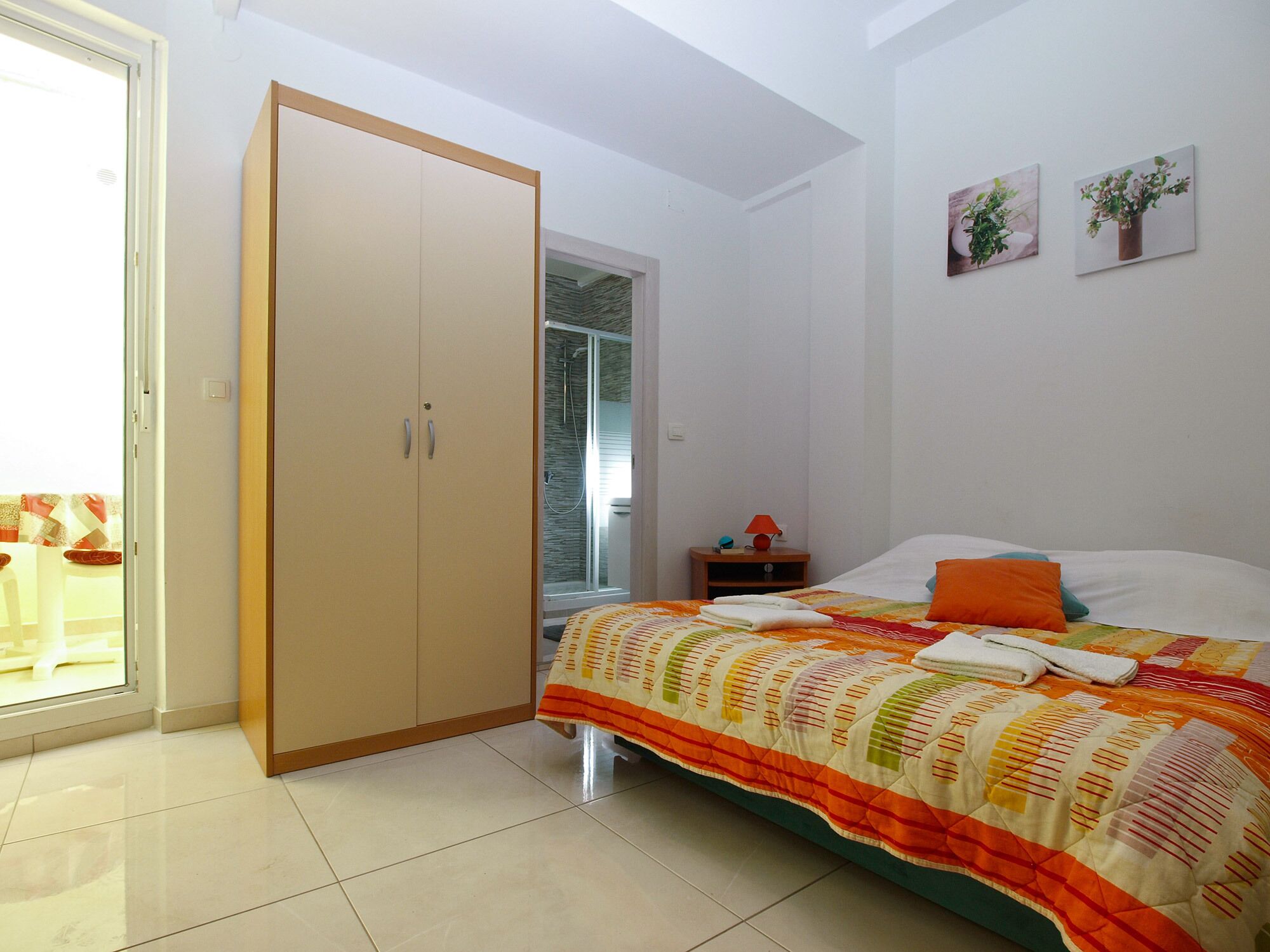 A bedroom with a bed, a wardrobe, a nightstand, and a window.