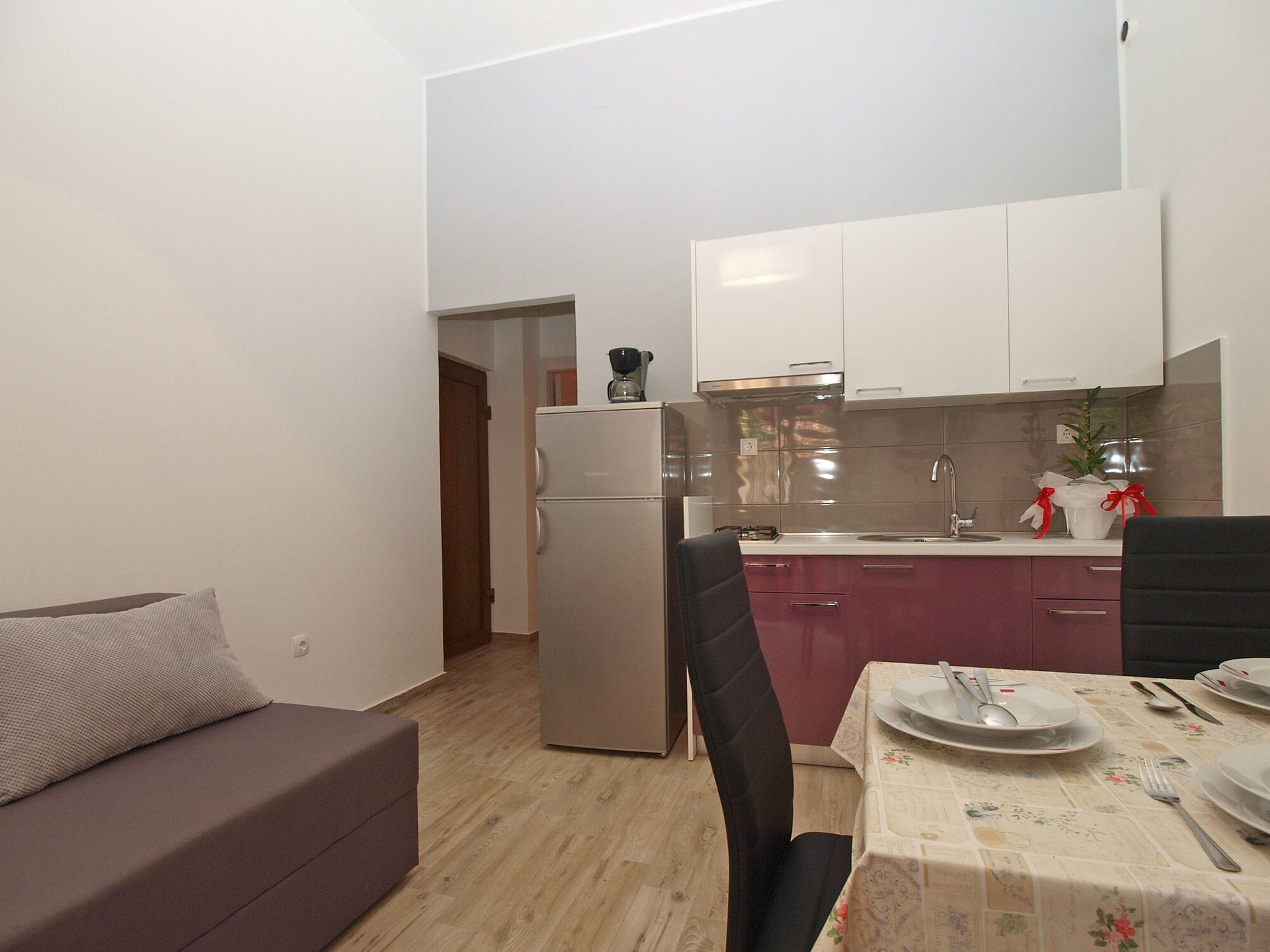 A compact living space with a kitchenette, a dining area with a table set for two, and a sofa.