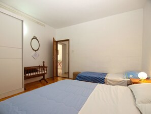 A bedroom with a large bed, a smaller bed, a wooden chair, a mirror, and a door leading to another room. - Apartments Petar 1306 (Fazana)