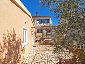 A courtyard with a tiled floor, a pergola, and a building with a satellite dish. - Apartments Petar 1306 (Fazana)