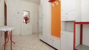 Een kamer met een bed, een kaptafel met spiegel, een klein tafeltje en een garderobe met een oranje accentpaneel.