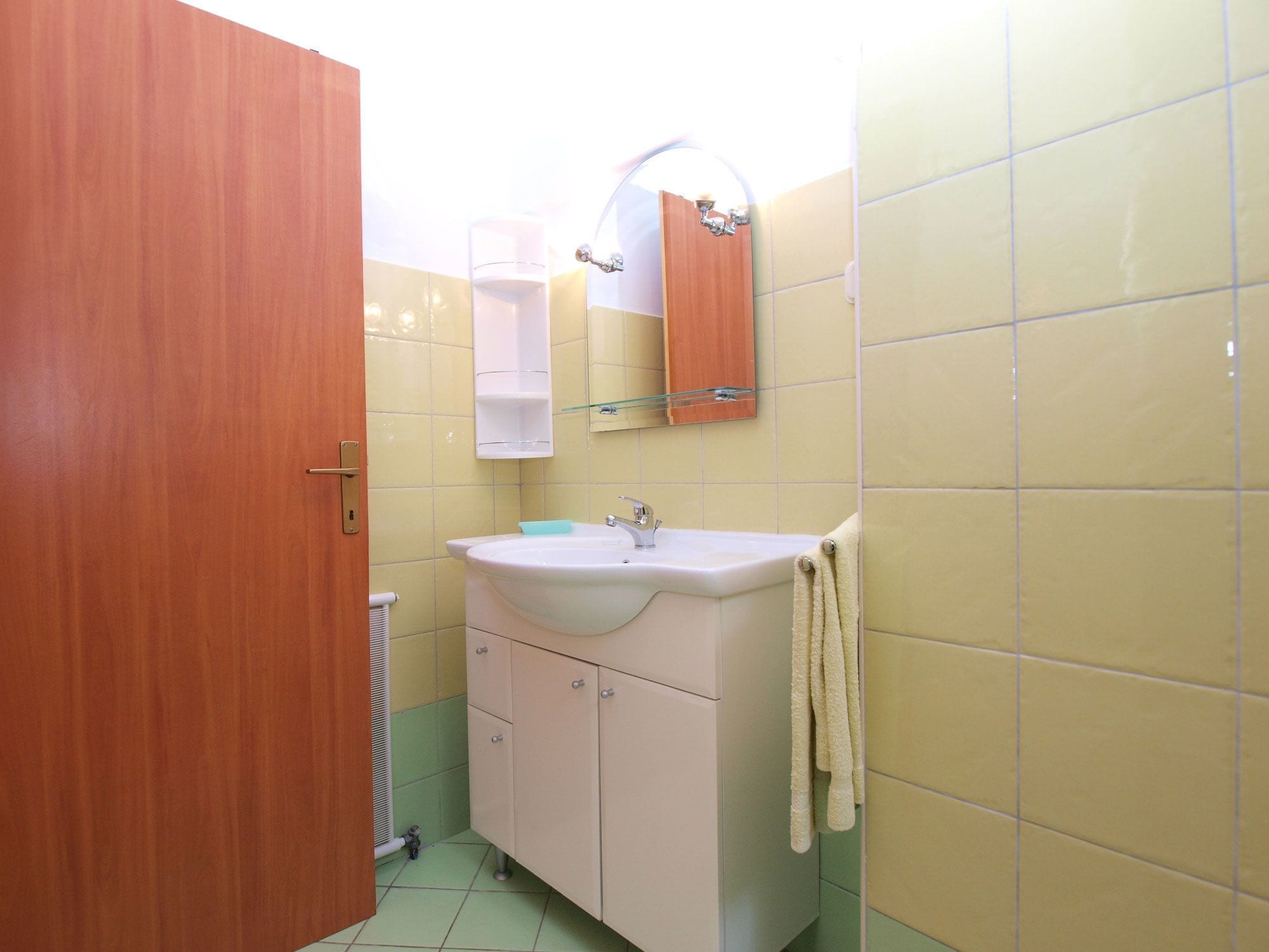 Een badkamer met een houten deur, een wastafel, een spiegel en een handdoek aan de muur.