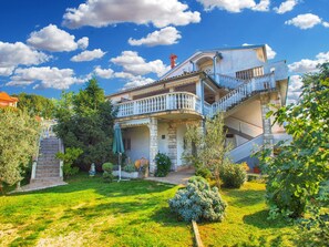 A two-story house with a balcony, a staircase, and a garden.