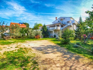A large, two-story house with a balcony, surrounded by a well-maintained garden and a gravel driveway. - Apartments Nadia 1493 (Medulin)