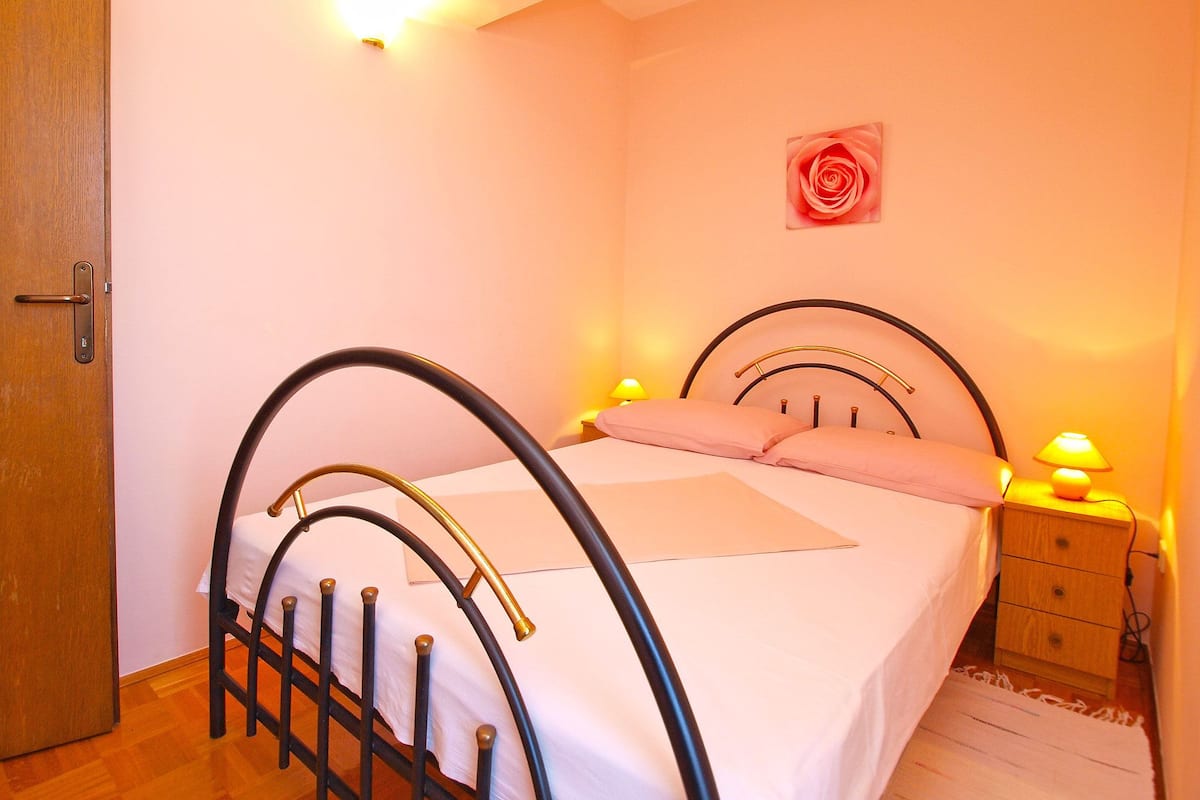 Une chambre à coucher avec un lit, une table de chevet, une lampe fixée au mur et une porte.