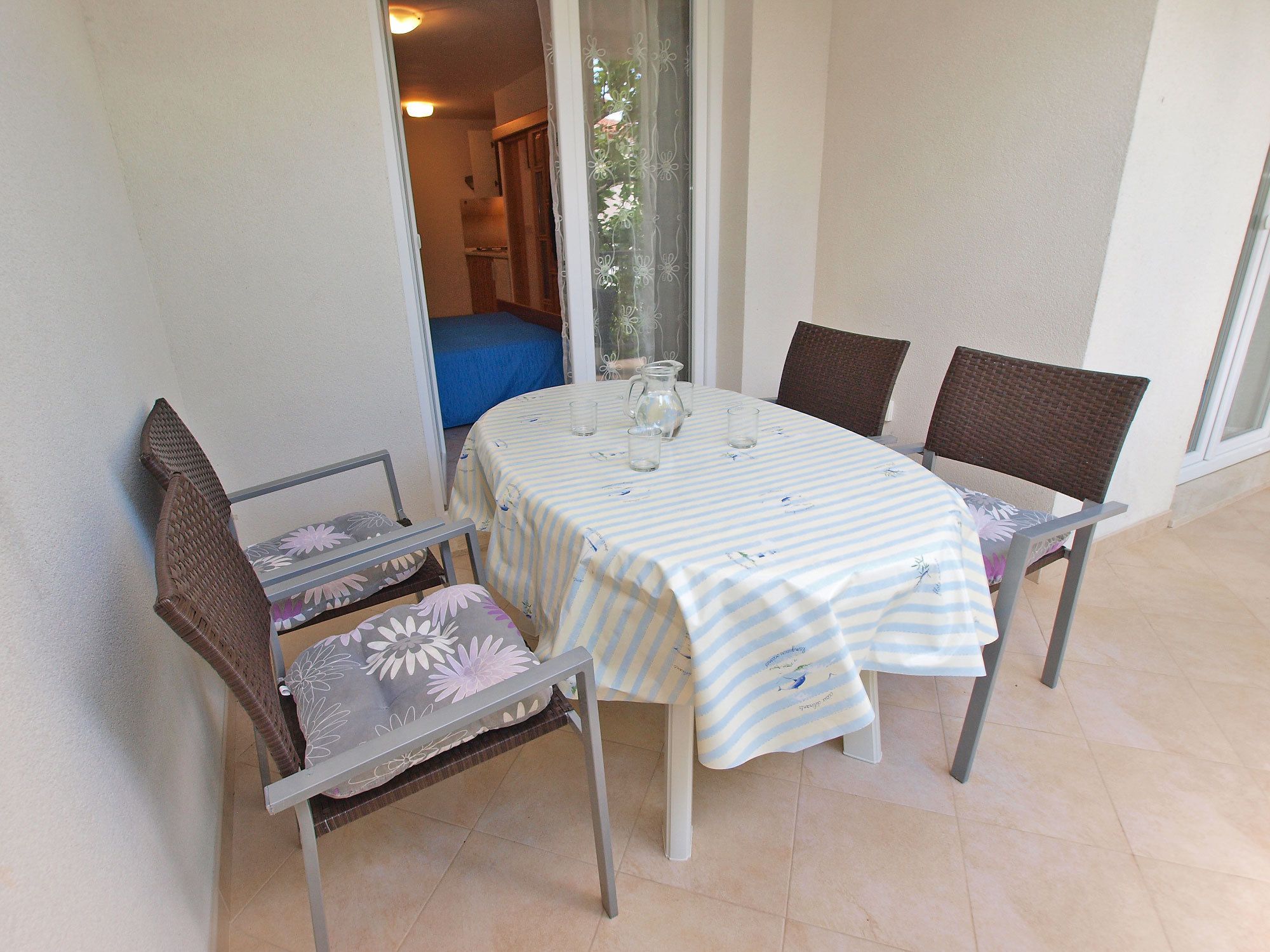 A dining area with a table set for four, two chairs on each side, and a bench with cushions.