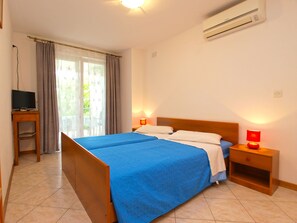 Une chambre d’hôtel équipée d’un lit, de deux tables de chevet, d’une télévision et d’un appareil de climatisation.