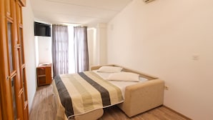 Een slaapkamer met een bed, een houten garderobe en een airconditioning.