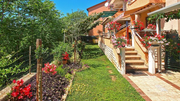 Un edificio con jardín, una escalera y una valla.