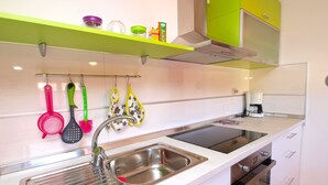Una cocina moderna con un lavaplatos de acero inoxidable, un horno empotrado y un estante verde sobre la encimera.