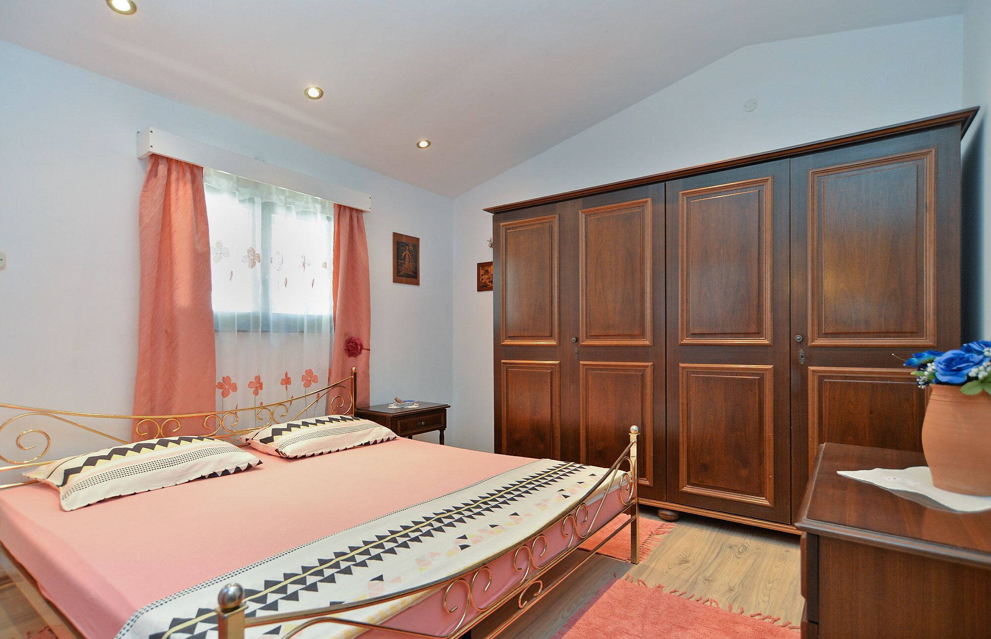 A bedroom with a bed, a wardrobe, and a window with curtains.