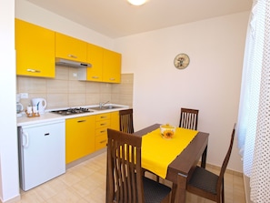 Uma cozinha compacta com armários amarelos, um fogão e uma mesa de jantar com cadeiras.
