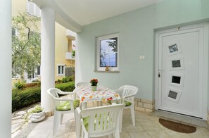 A patio with a table and chairs, a door with windows, and a small garden area. - Apartments Nelli 624 (Pula)