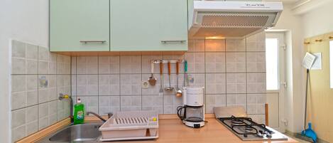 A compact kitchen with a gas stove, a coffee maker, and a sink.