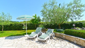 A patio with stone flooring, two striped lounge chairs, and a striped umbrella. - Apartments Nelli 624 (Pula)