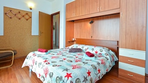 A bedroom with a bed, wooden wardrobe, cork bulletin board, and a nightstand. - Apartments Nelli 624 (Pula)