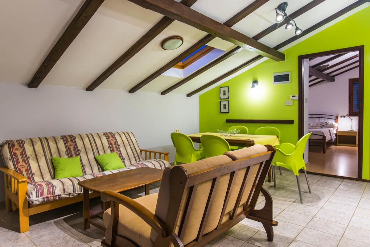 Una sala de estar acogedora con un sofá, una mesa de madera y sillas verde brillante.
