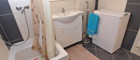 Et badeværelse med badekar, vask, toilet og et spejl.