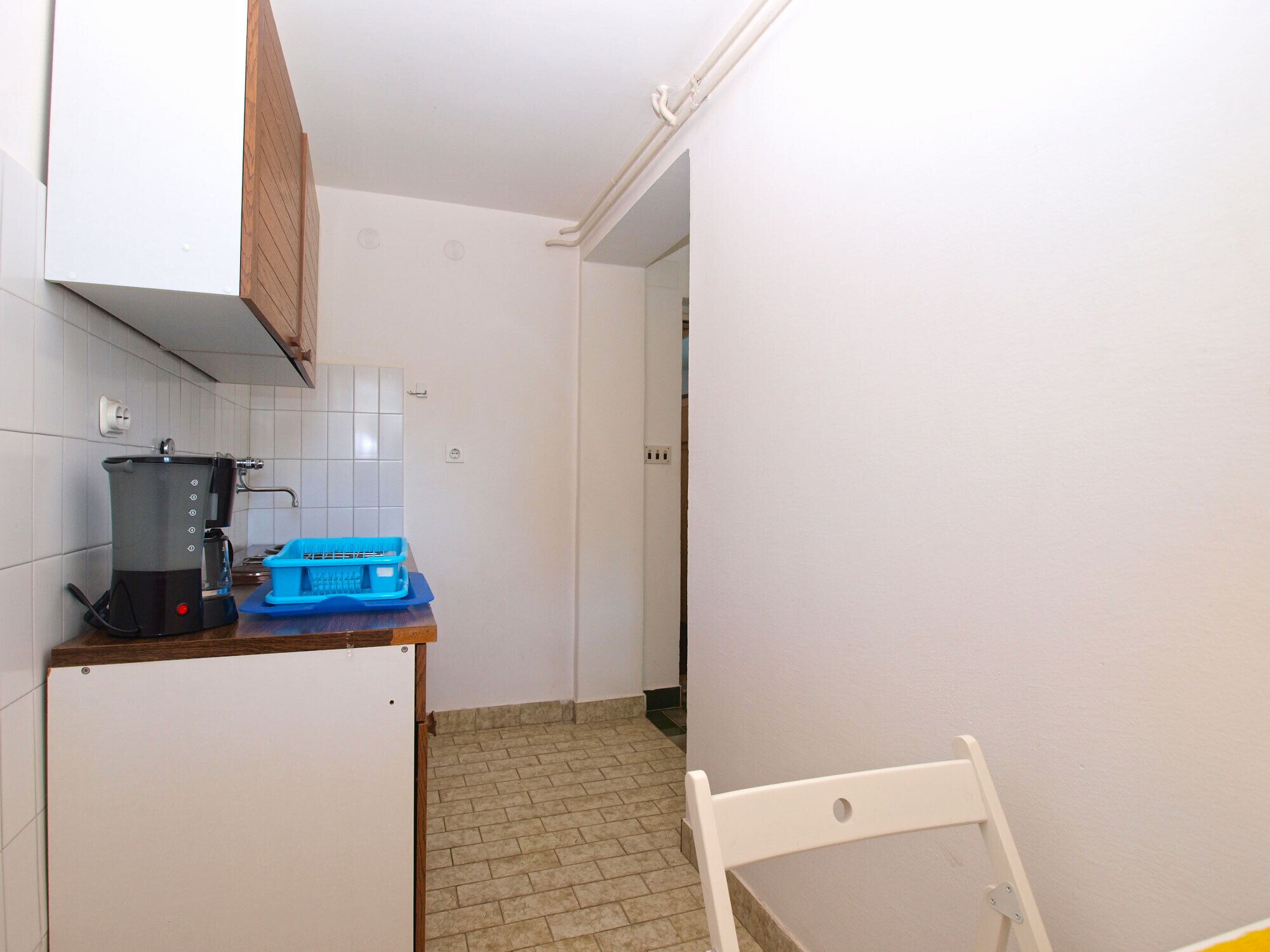A compact kitchen with a coffee maker, a blue container, and a white refrigerator.