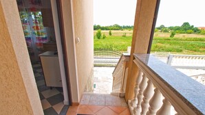 A balcony with a view of a green field and a white railing. - Apartments Lillies 1390 (Fazana)