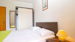 Ein Hotelzimmer mit Bett, Nachttisch mit Lampe, Kleiderschrank und einem gerahmten Bild an der Wand.
