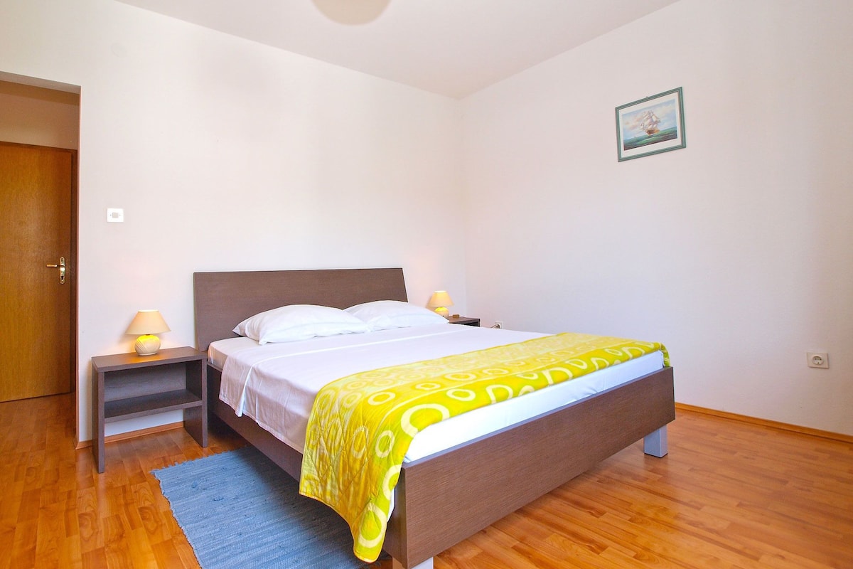 A bedroom with a bed, bedside tables, a rug, and a painting on the wall.