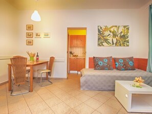 Una habitación compacta con cama, mesa de comedor y kitchenette.