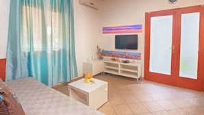 A living room with a sofa, a coffee table, a TV, and a red door. - Apartment Fatima 1514 (Pula)
