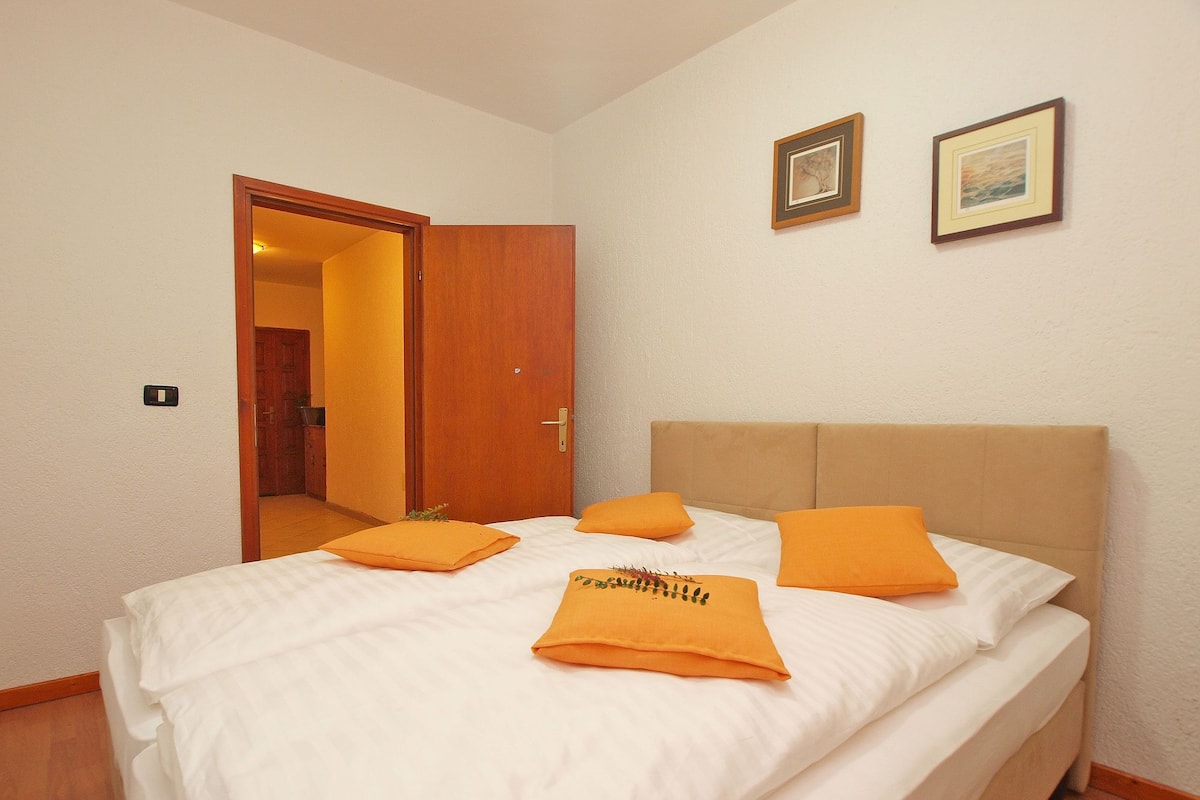 Una habitación de hotel con una cama, una puerta de madera y dos cuadros en la pared.