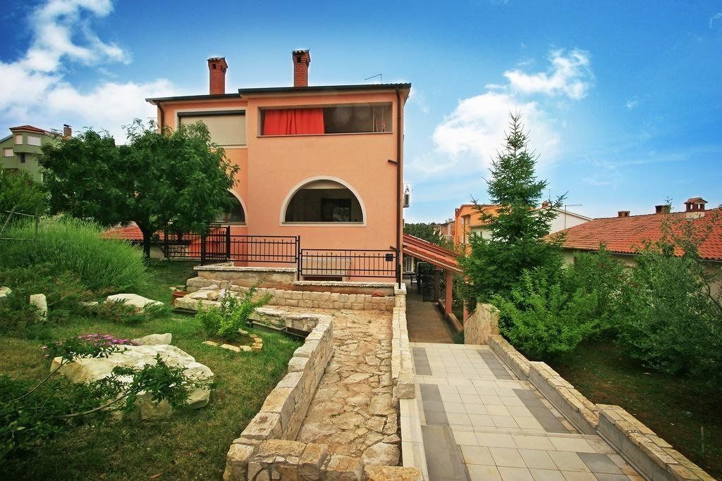 A two-story building with a stone pathway leading to the entrance.