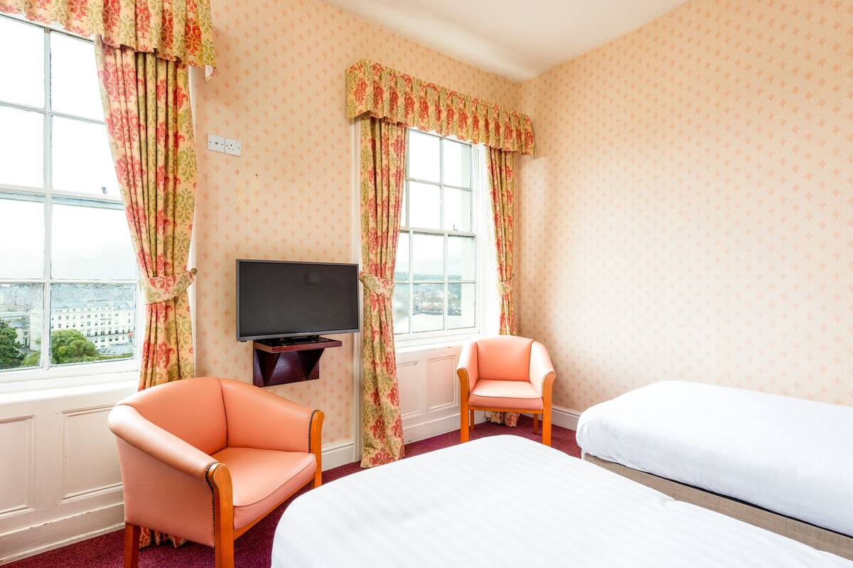 A hotel room with two beds, a television, and two chairs.