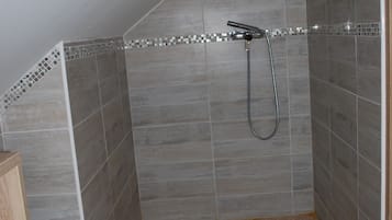 A small, tiled shower area with a showerhead and a toilet.