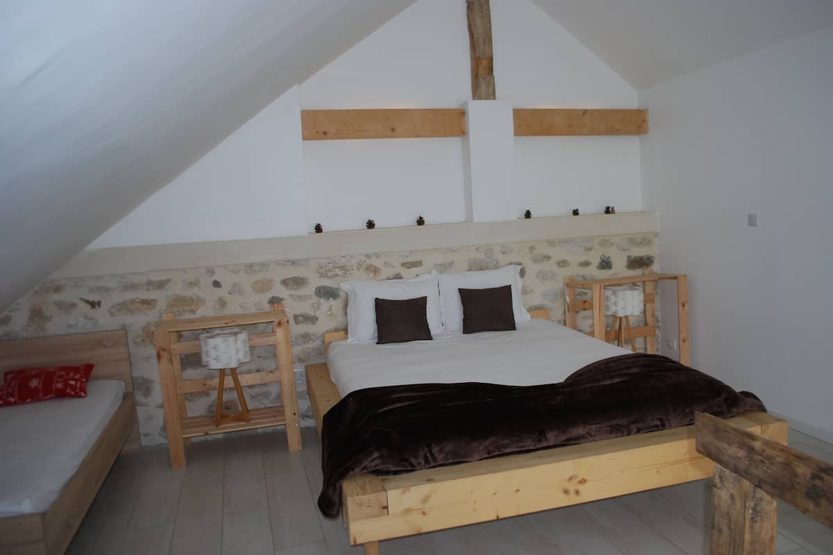 Un dormitorio con una cama de madera, una pared de piedra y techo inclinado.