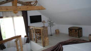 Une chambre rustique avec un lit, des meubles en bois, une télévision et une fenêtre avec des rideaux.