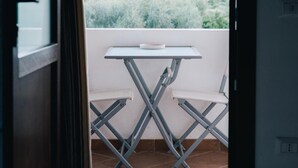 Un balcon avec une table et des chaises, offrant une vue sur un paysage montagneux.