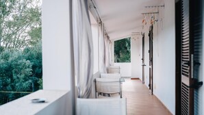 Un couloir donnant sur des arbres, avec une table et des chaises.