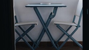 Un balcon avec une table et deux chaises, donnant sur un paysage montagneux.